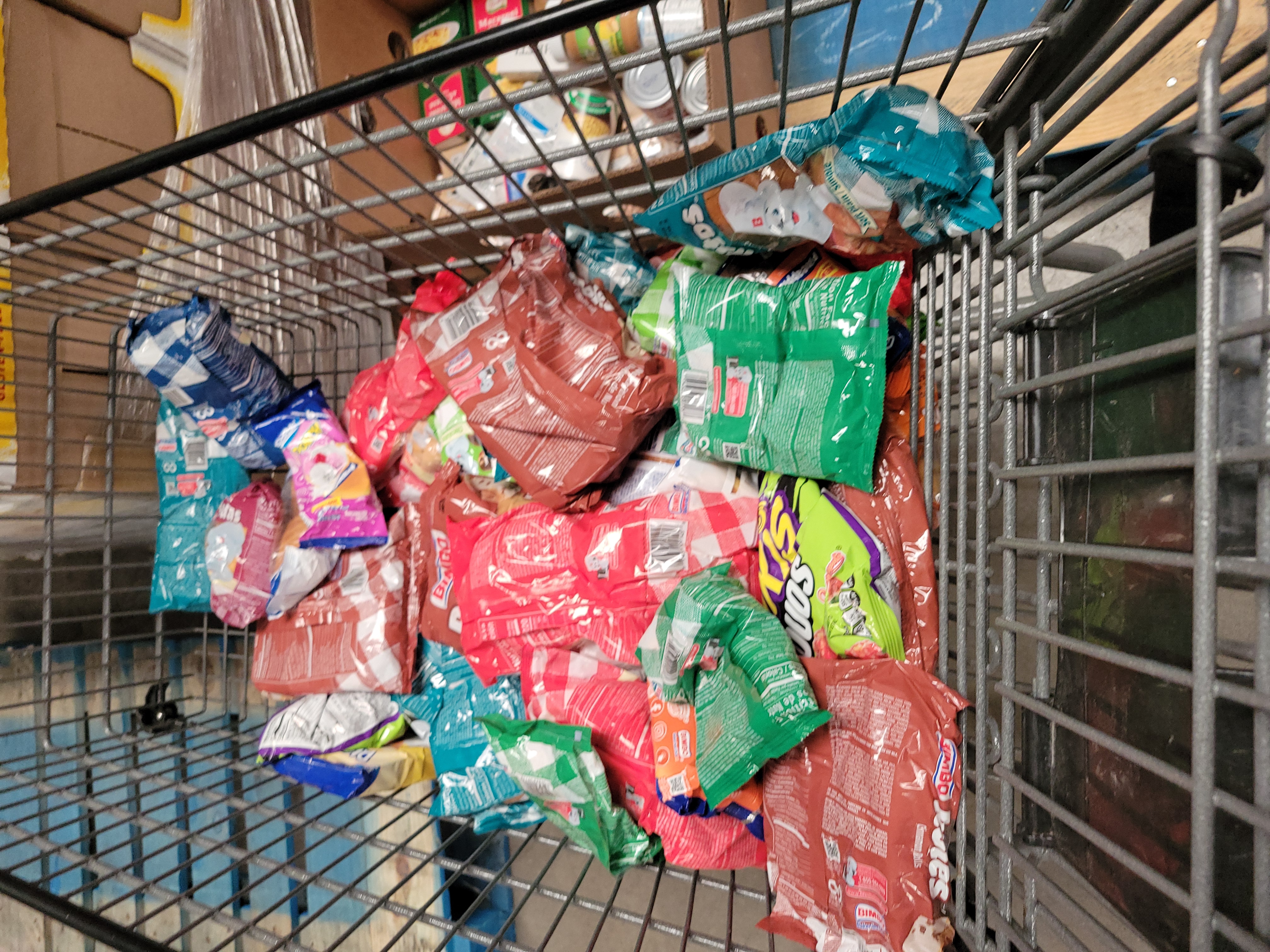 Bags of chips and sweets in a shopping cart.